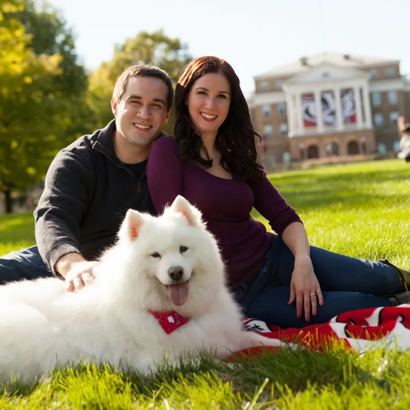 Happy couple sitting with their big white dog